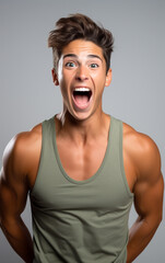 A beautiful muscular guy in singlet with an excited and surprised expression, isolated on background