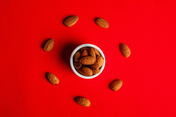 Almonds seed in white cup on red background