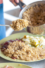 A woman prepares oatmeal with fruits, close-up.