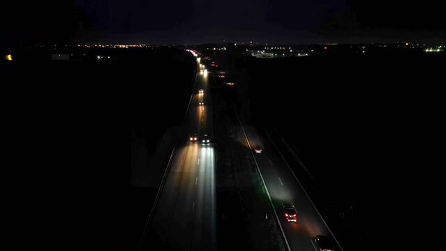 Aerial view of cars driving on a dual carriageway on dark, lights falling on the road, night car traffic.