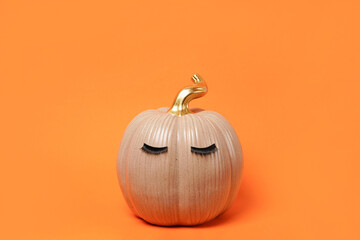 Halloween Pumpkin with false eyelashes on bright orange background. Autumn, fall, beauty concept. copy space