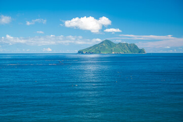 Blue sea and blue sky with changing white clouds. Small islands and rocks. Guishan Island(Turtle...
