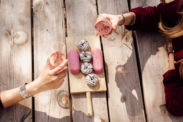 Hands of women with wineglasses at picnic table