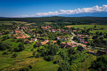 Drone photograph of Somartin old saxon village in Transylvania. Fagaras Mountains in the background. - obrazy, fototapety, plakaty