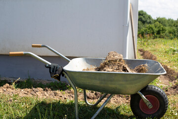 Excavation of earth around the house for the construction of a blind area
