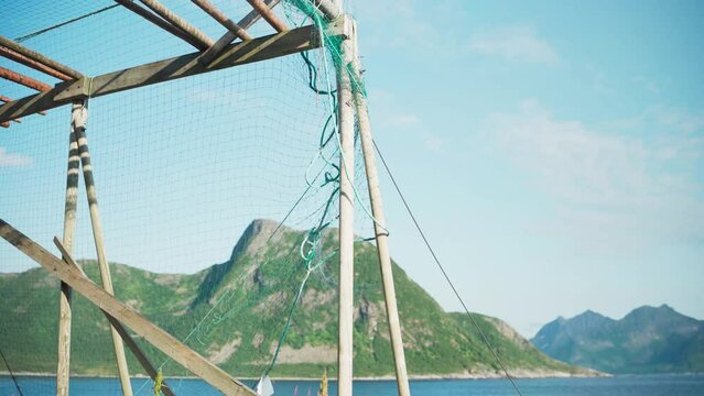 Cod Fish Drying Rack With Net On The Shore In Grunnfarnes, Senja Island, Norway. tilt