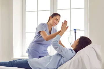 Zelfklevend Fotobehang Friendly female gynecologist doctor giving high five to her pregnant woman patient lying on the couch in medical clinic and receiving IV drip infusion and vitamin therapy. Healthy pregnancy concept. © Studio Romantic