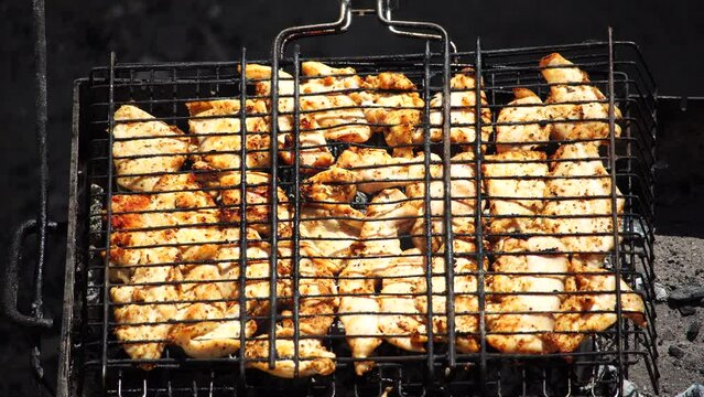 close-up of flattened out barbecued golden crispy skin chicken tabaka on grid, side view from above