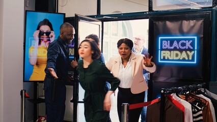 Shoppers push red tape entering store, looking to buy clothes during black friday big sales....