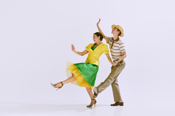 Attractive, positive young couple, man and woman in stylish clothes dancing isolated on white...