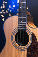 Fototapeta premium Close-up, acoustic guitar on a dark background with bokeh lights.