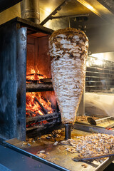 Grilled chicken meat on a vertical rotisserie used in traditional turkish street food Doner Kebab,...