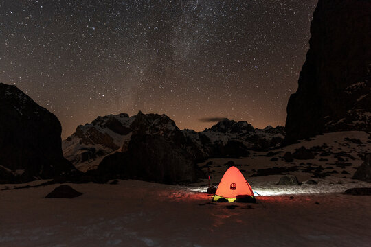 Illuminated tent under milky way night landscape in mountain range