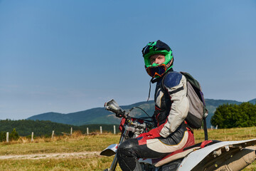 A professional motocross rider, fully geared up with helmet, gloves, and goggles, sits poised on their motorcycle, ready to embark on a thrilling training session through the challenging forest