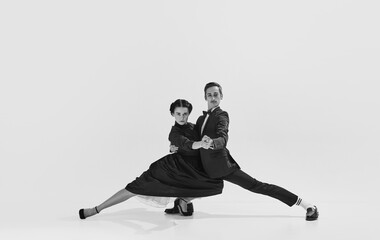 Talented and artistic young man in suit and beautiful woman in elegant dress dancing lindy hop. Black and white. Concept of hobby, retro dance, vintage style, choreography, beauty. Monochrome art. Ad