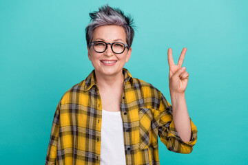 Portrait of charming middle age lady showing v sign symbol saying hi to colleagues office isolated...