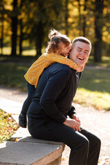 Joyful dad hugs his little smiling daughter. Single daddy and child have fun, laugh and enjoy nature outdoors at autumn park. Concept of parental care and happy carefree childhood. Happy fathers day