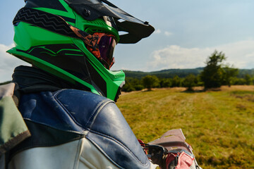 A professional motocross rider, fully geared up with helmet, gloves, and goggles, sitting poised on...