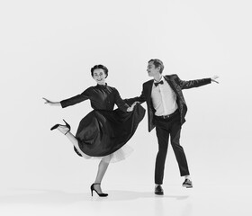 Black and white. Happy, positive, smiling young people, man and woman in elegant clothes dancing lindy hop. Concept of hobby, retro dance, vintage style, choreography, beauty. Monochrome art. Ad