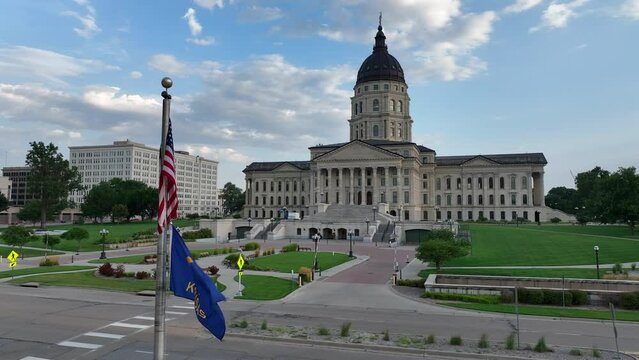 Kansas state flag waving in front of capitol building in downtown Topeka, KS. Aerial establishing shot on a beautiful summer evening.