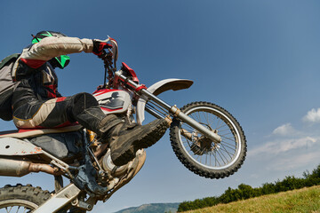 A fearless professional motocross rider skillfully executes an extreme back wheelie maneuver...