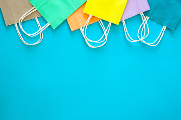 Paper bags of different colors on a blue background, top view.