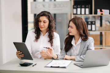 Two businesswoman discuss investment project working and planning strategy with tablet laptop...