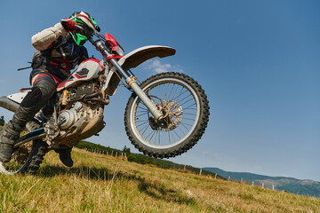 A fearless professional motocross rider skillfully executes an extreme back wheelie maneuver...