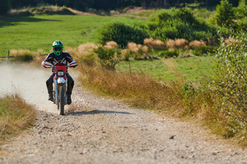 A professional motocross rider exhilaratingly riding a treacherous off-road forest trail on their...