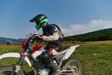 A motorcyclist equipped with professional gear, rides motocross on perilous meadows, training for...