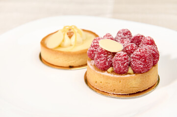 Still life with a raspberry and lemon meringue tartlets isolated over white background. Close-up
