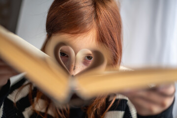 A girl is holding a book. Heart-shaped pages. Reading, Knowing, Learning