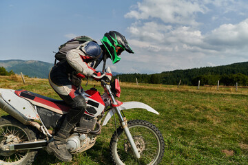 A motorcyclist equipped with professional gear, rides motocross on perilous meadows, training for...