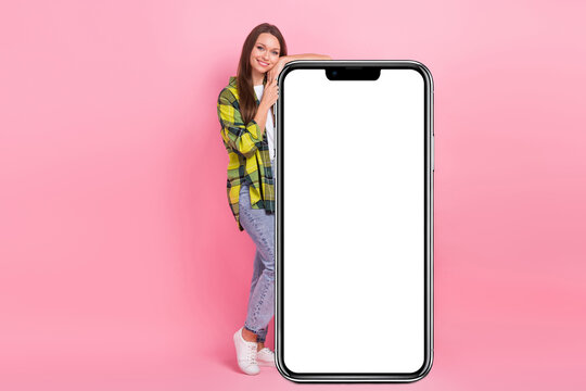 Full length photo of beautiful girl wear casual trendy look hands over big smartphone display eshopping web promo isolated on pink color background