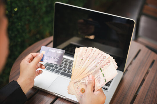 Woman using working and shopping outdoor at cafe coffee shop, Online e-commerce, internet banking, Hands of businesswoman holding thai money and credit card on laptop computer, technology finance