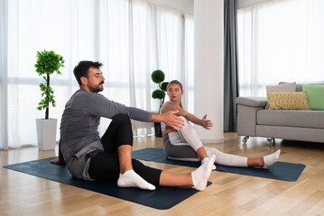 Couple exercising together. Man and woman in sportswear doing workout at home. Partners doing yoga...