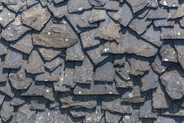 Detailed view of wall texture randomly lined with slate panels, typical and traditional shale stone material, used as external waterproof cladding in construction