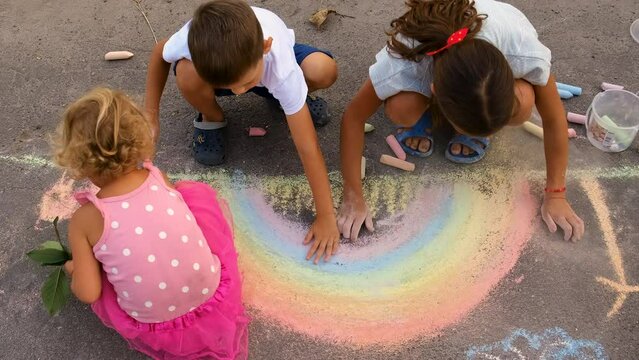 Children draw a rainbow with chalk on the pavement. Selective focus.