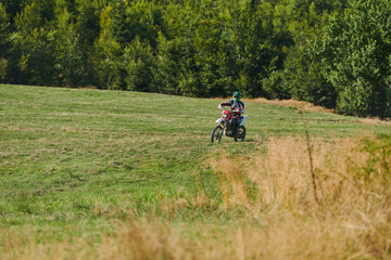 A professional motocross rider exhilaratingly riding a treacherous off-road forest trail on their...