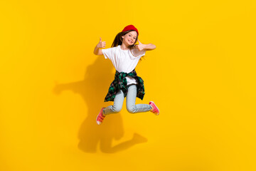 Fototapeta na wymiar Full length photo of charming little girl showing double thumb up jumping wear trendy white garment isolated on yellow color background