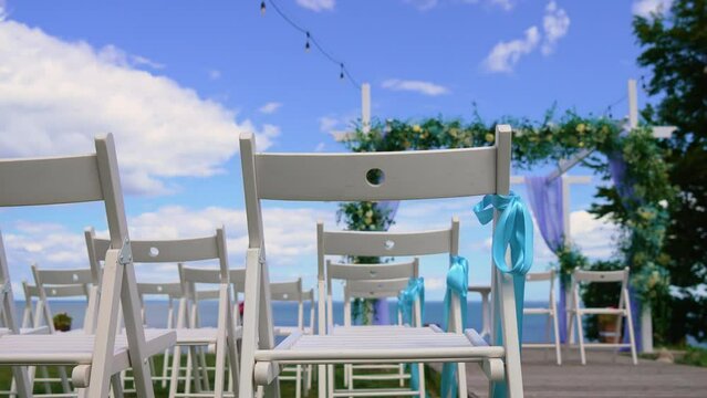 Wedding decor at seaside floral roses arch sunny summer. Best Wedding details with Wood chairs. Setting stage festive marriage patterns