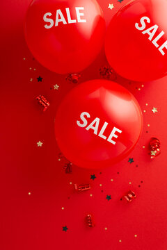 Holiday Savings Event: Top view vertical image featuring "sale" balloons, glowing confetti, and an inviting red background for your promotion