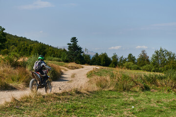Obraz premium A professional motocross rider exhilaratingly riding a treacherous off-road forest trail on their motorcycle.
