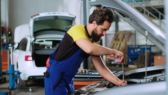 Mechanic in car service uses torque wrench to tighten bolts inside vehicle after fixing components inside. Repair shop employee utilizing professional tools to make sure automobile is properly working