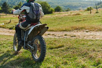 Fototapeta na wymiar A motorcyclist equipped with professional gear, rides motocross on perilous meadows, training for an upcoming competition.