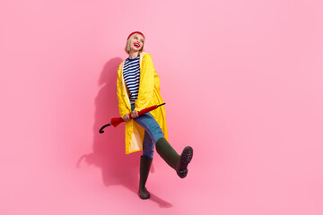 Fototapeta na wymiar Full length photo of cheerful positive lady wear raincoat walking umbrella looking empty space isolated pink color background
