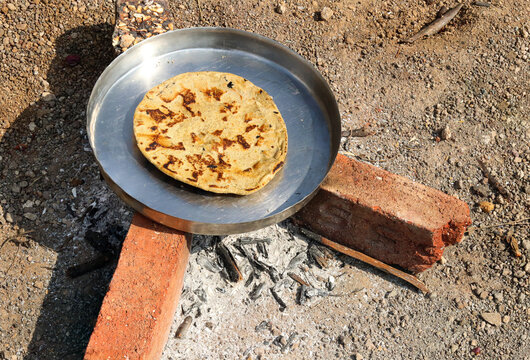 Open fire cooking in Gujarati village traditional sorghum ki roti or pearl millet flat bread. farmer's lunch which are bajre ki roti. Jowar Roti or Indian bread, making on WOOD STOVE (Desi chulha).