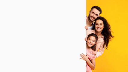 Family offer. Excited european parents and their daughter peeking out of blank white board with free space for your ad - obrazy, fototapety, plakaty