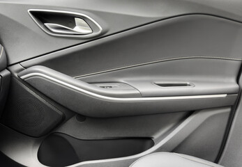 Door handle with Power window control buttons of a luxury passenger car. Black leather interior of...