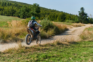 A professional motocross rider exhilaratingly riding a treacherous off-road forest trail on their...